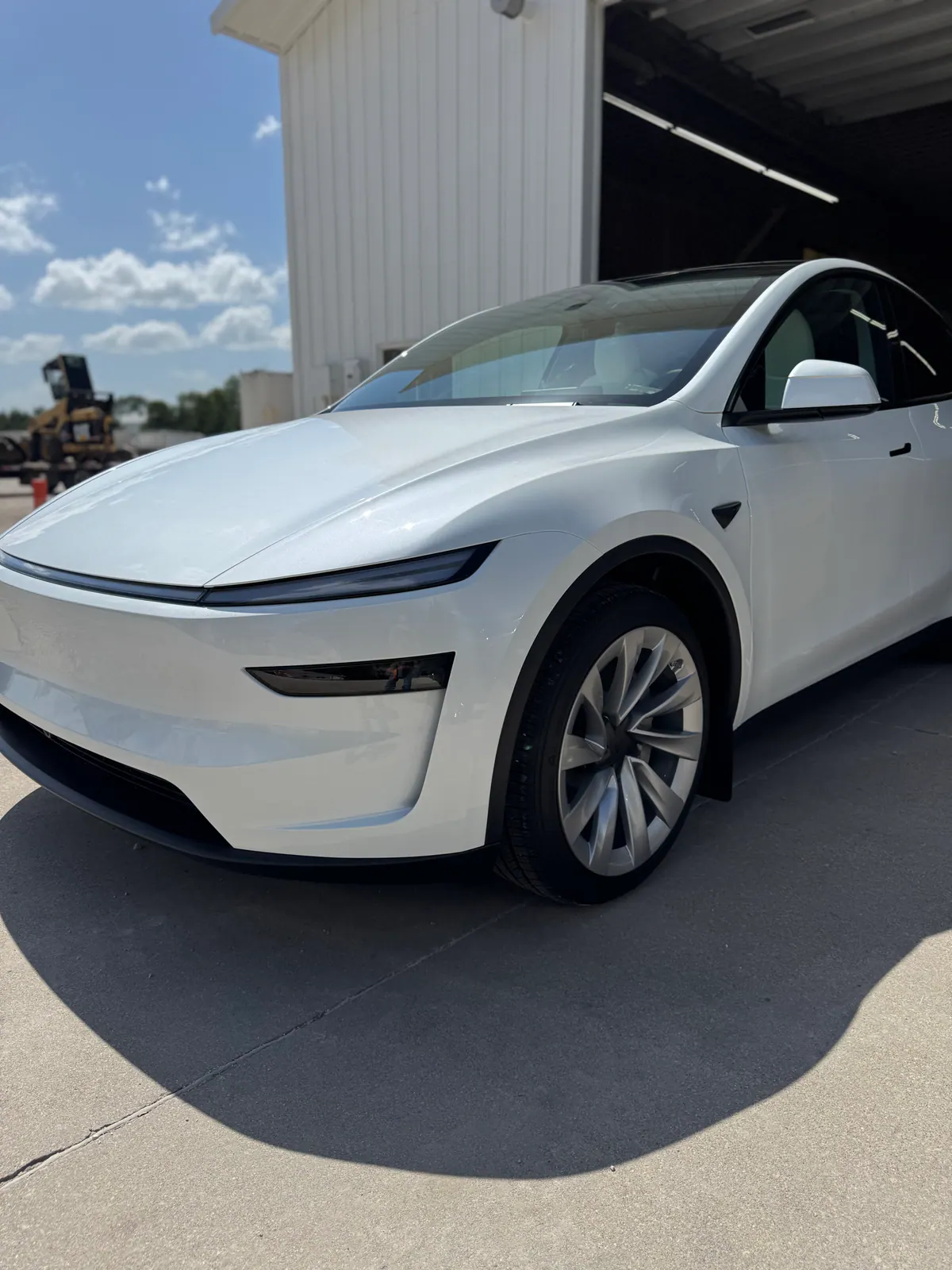 White Tesla SUV parked at the entrance to a detailing shop