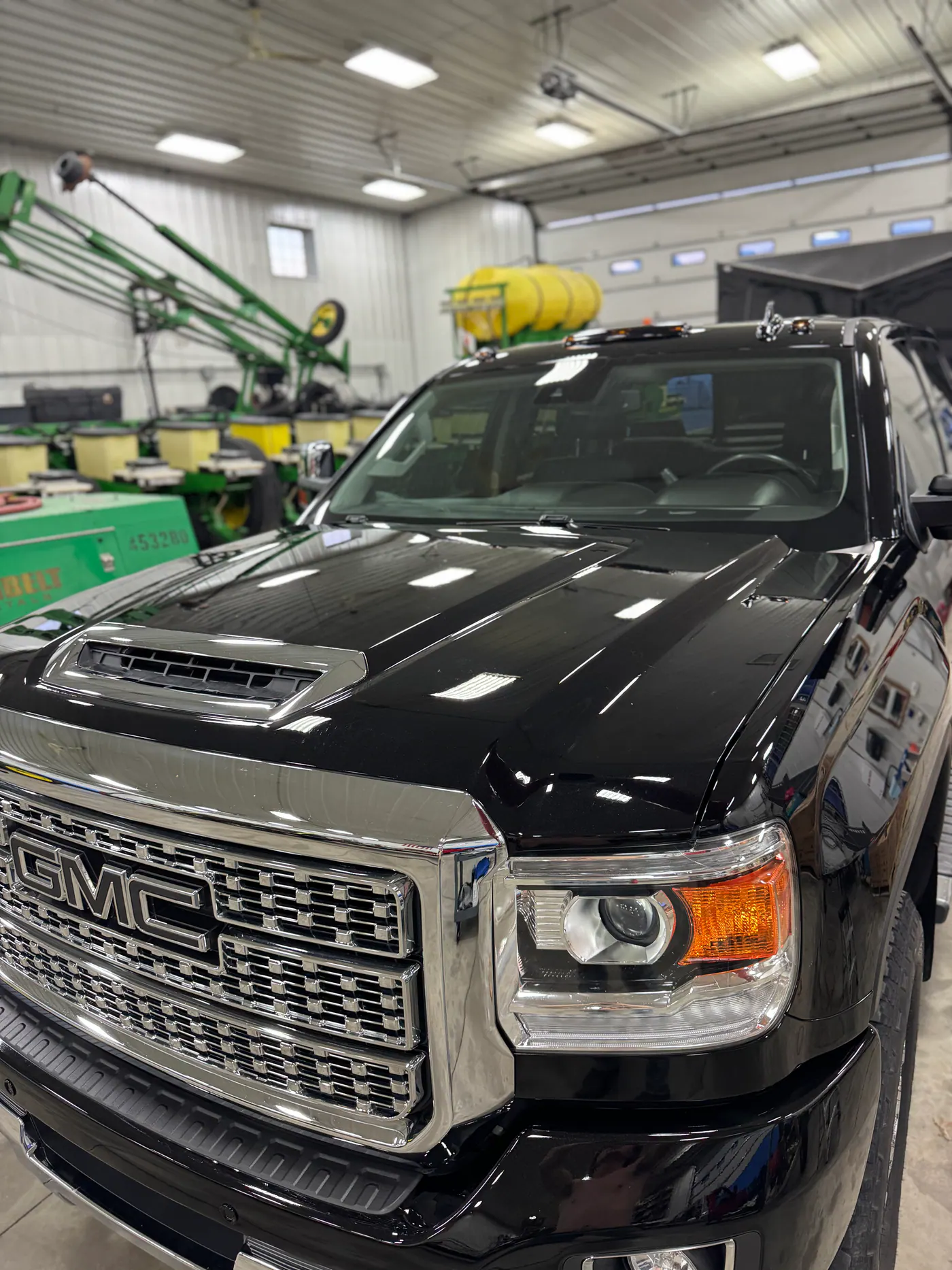 Black GMC pickup front end inside an equipment shop