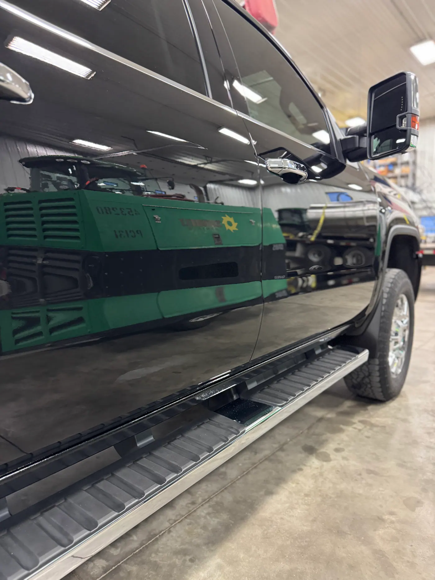 Reflective black GMC pickup door and side step in a shop