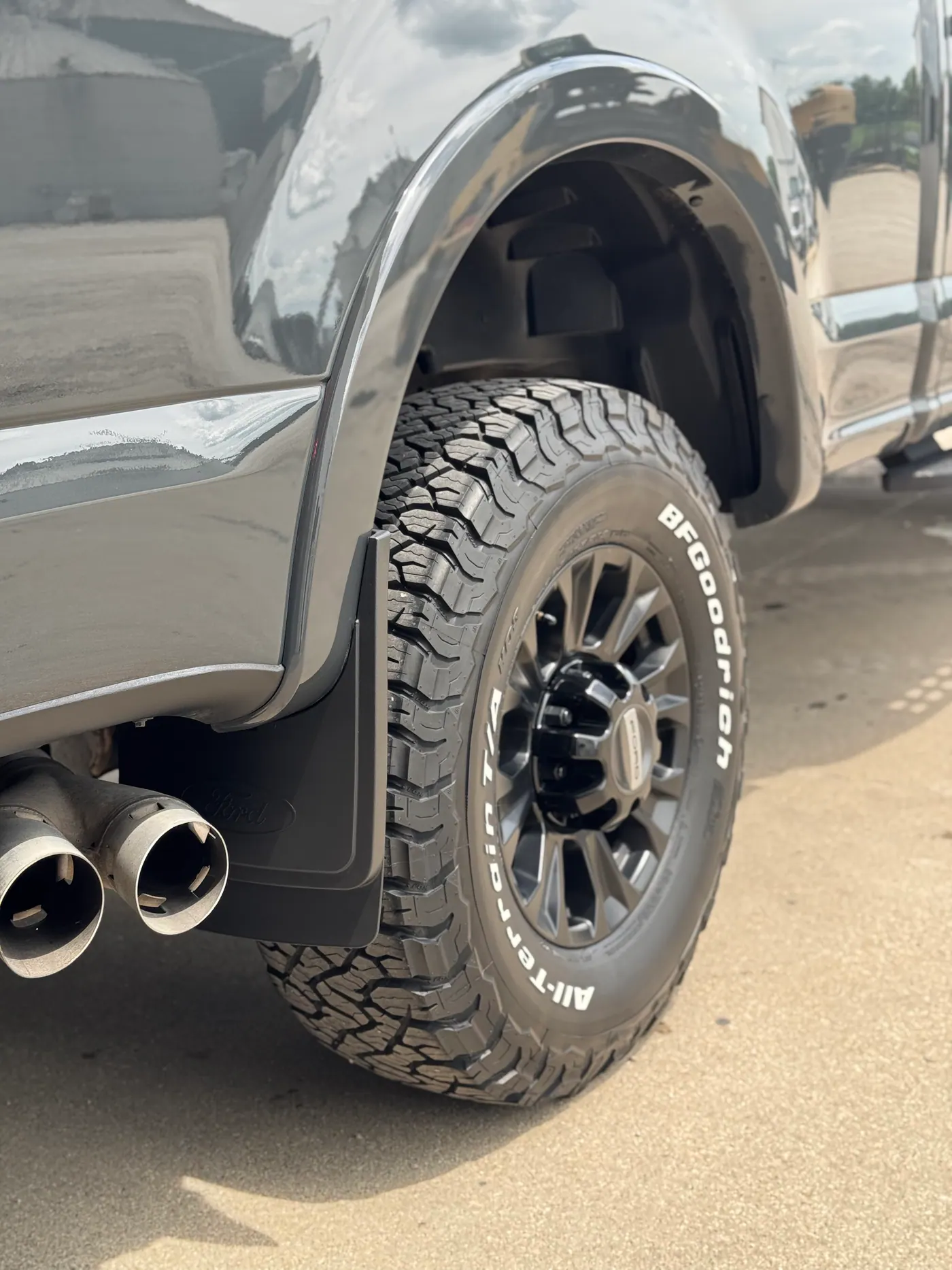 Rear wheel and glossy body panel of a black Ford pickup