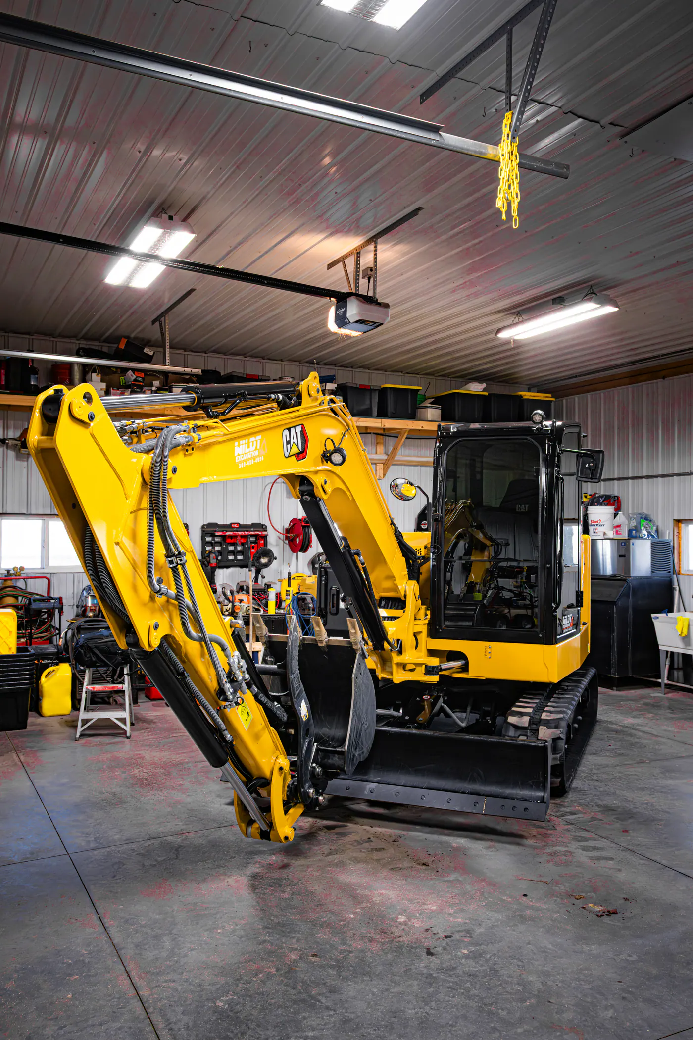 Yellow tracked excavator parked inside a working garage