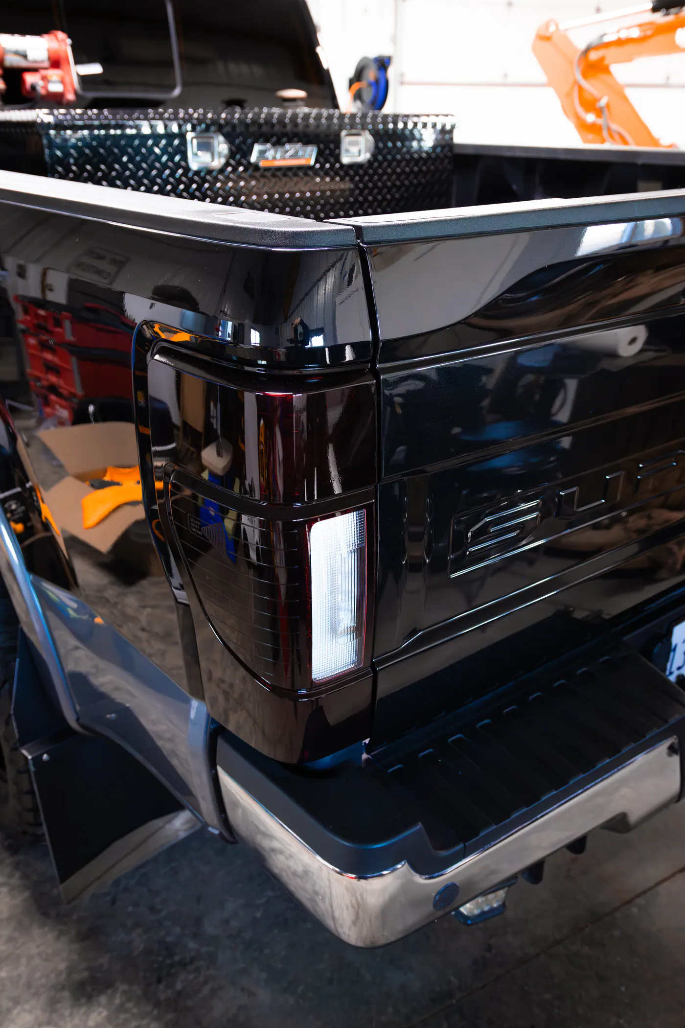 Glossy black Ford pickup tailgate and dark taillight in a shop