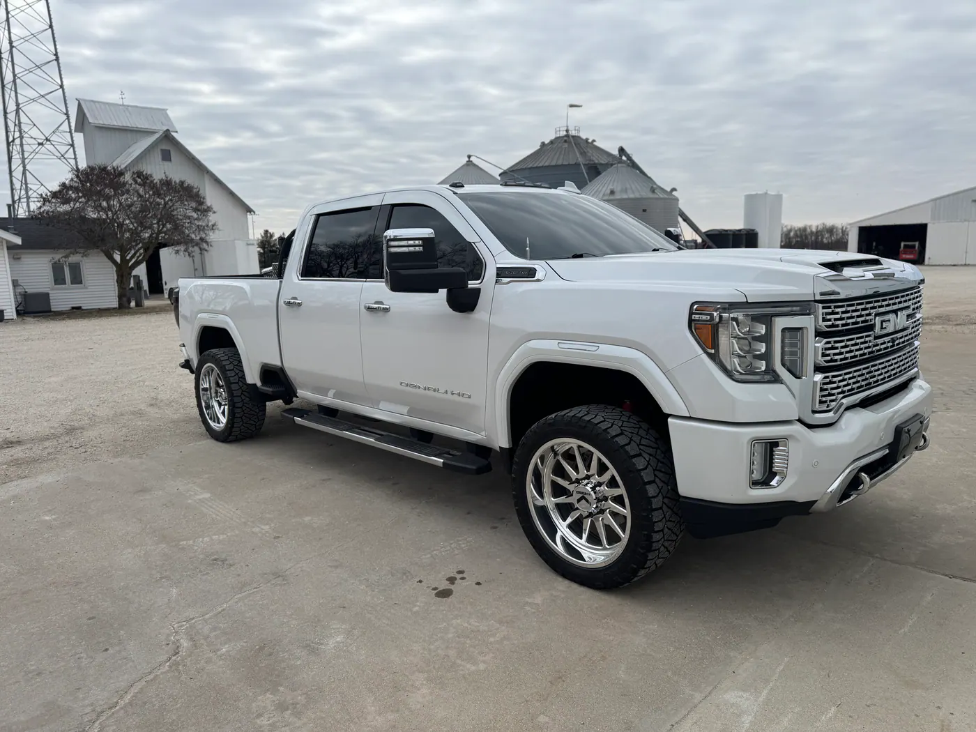 White GMC Denali HD pickup parked near farm buildings