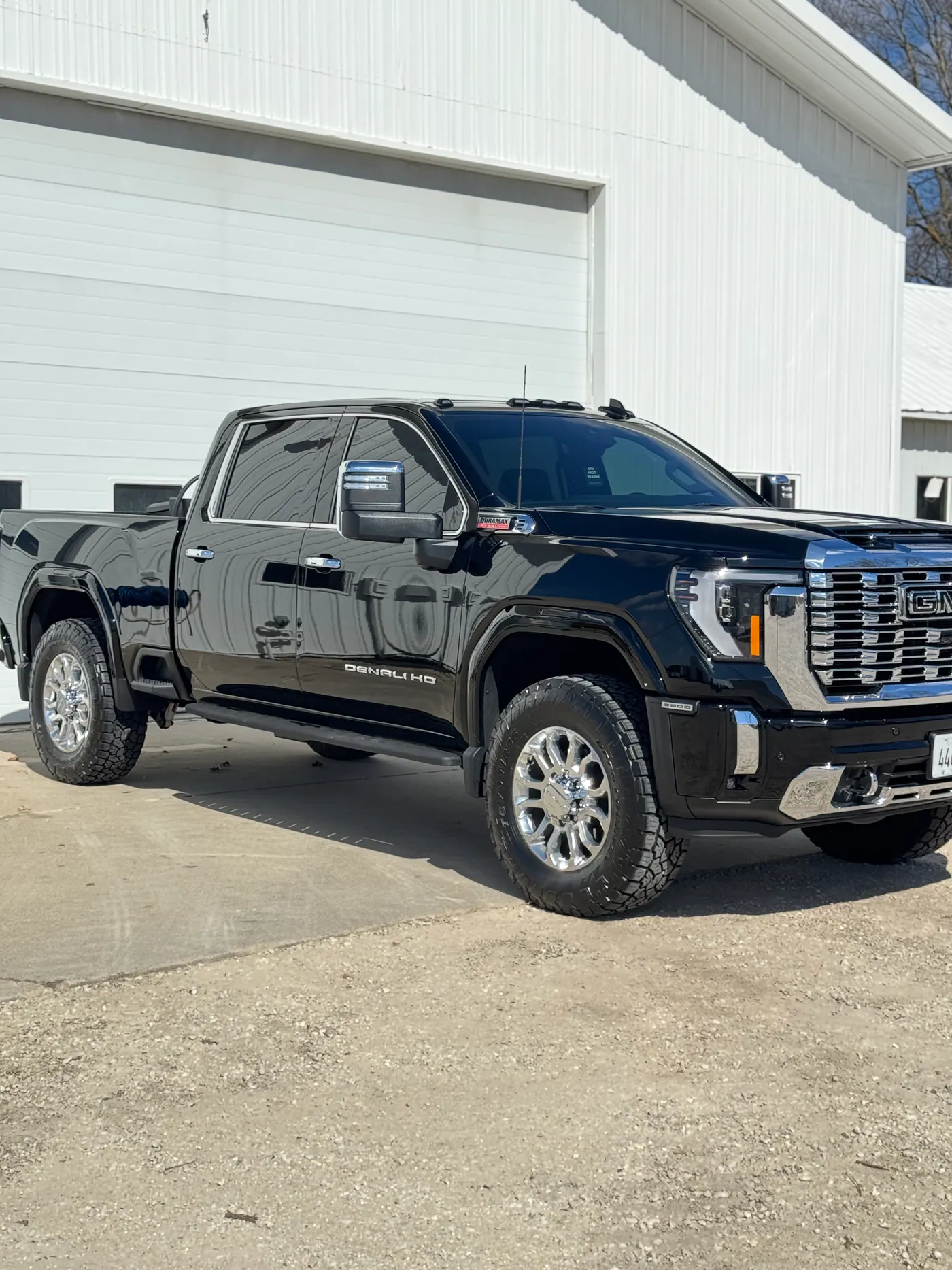 Black GMC Denali HD pickup parked outside a white building