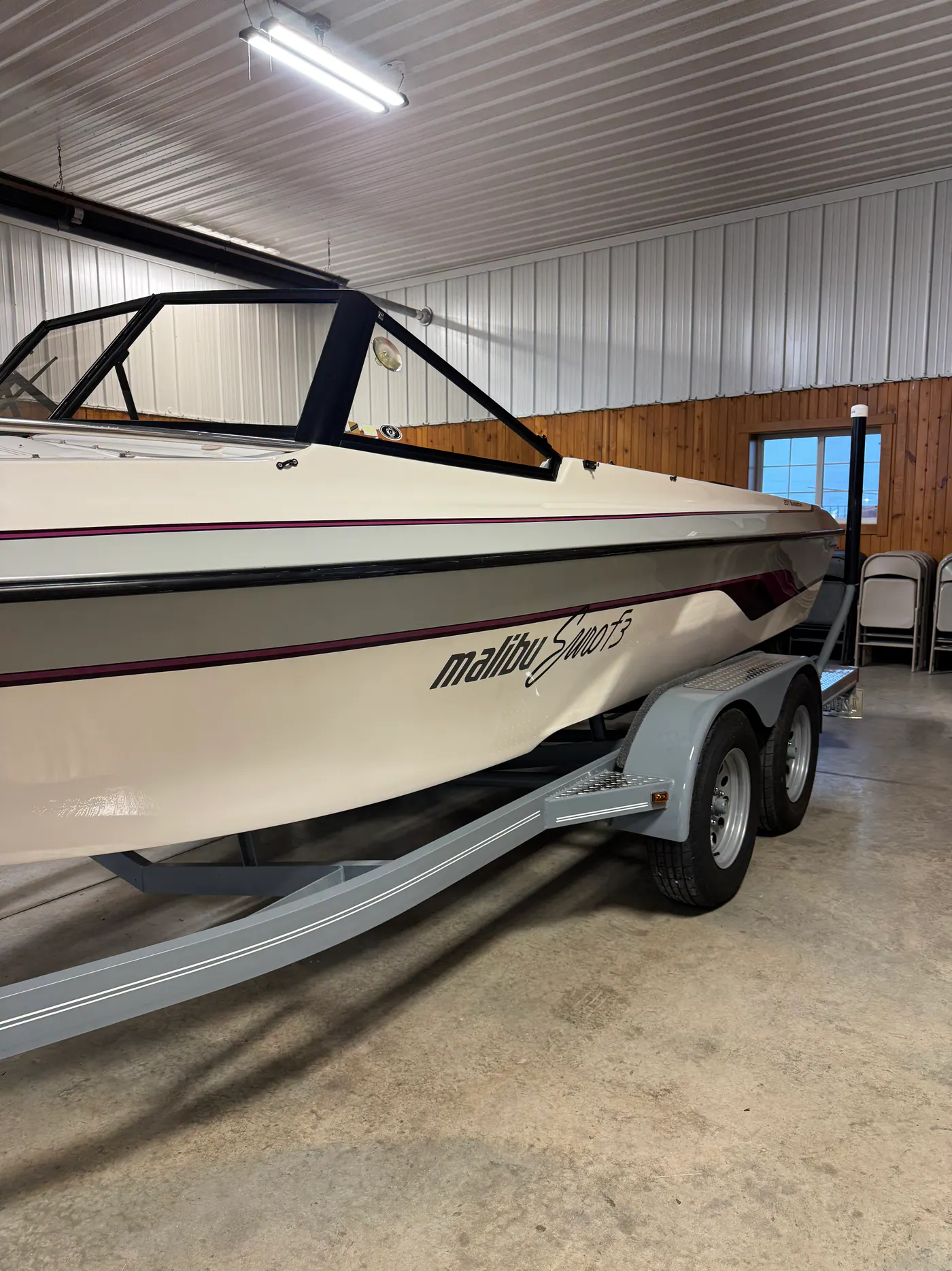 White Malibu Sunset boat on a trailer inside a shop