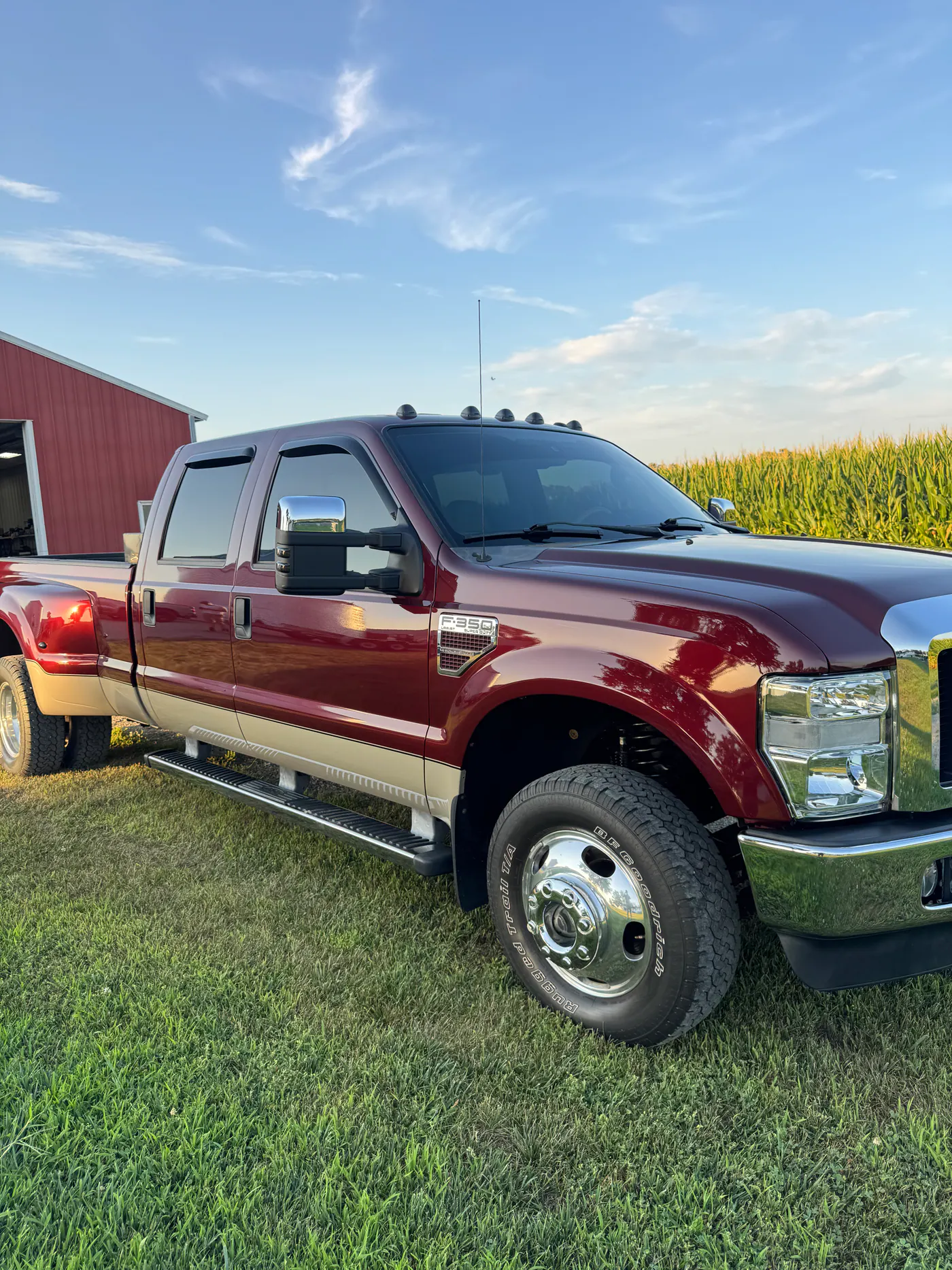 Burgundy Ford dually pickup parked beside a cornfield