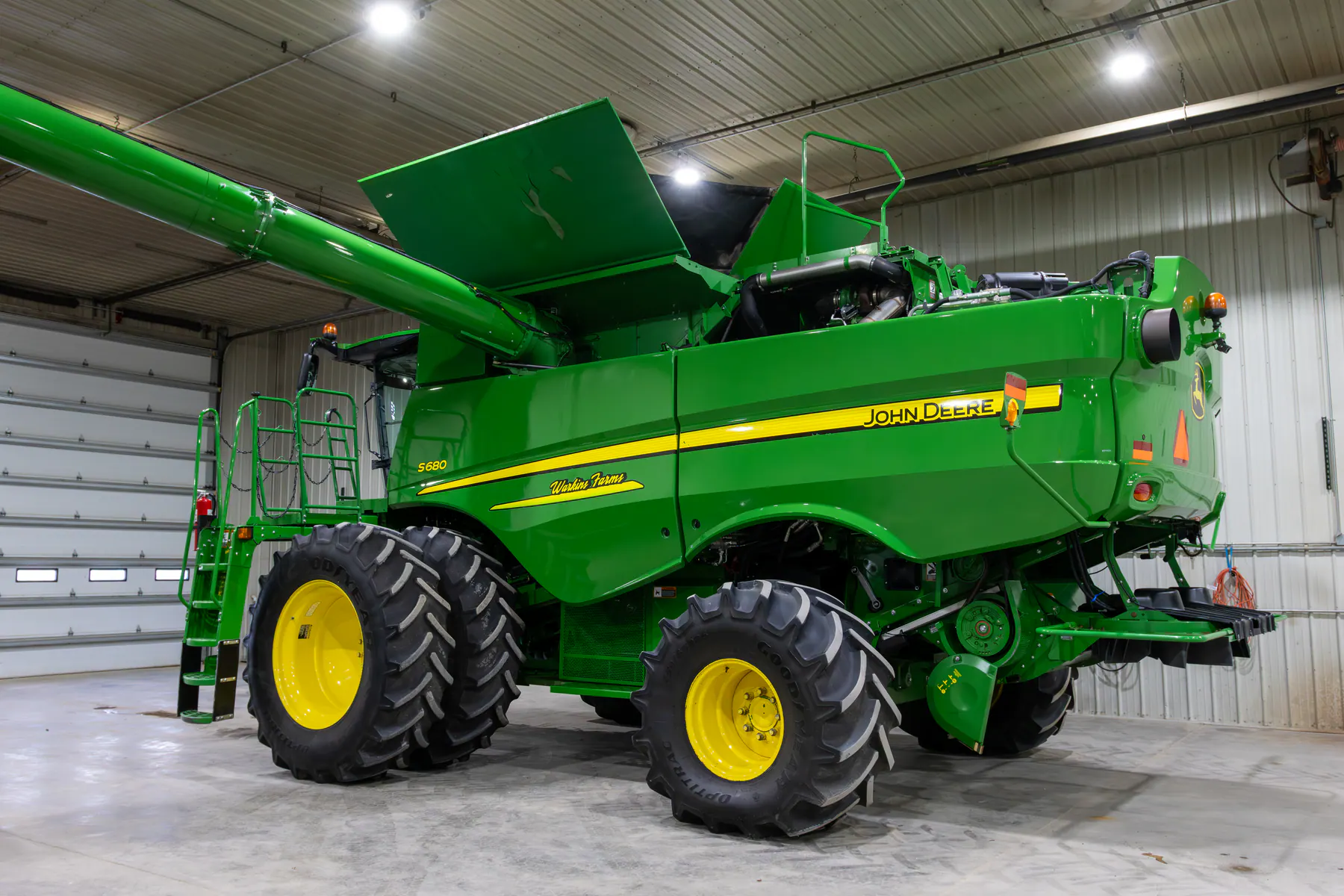 Green John Deere combine with clean body panels inside a shop