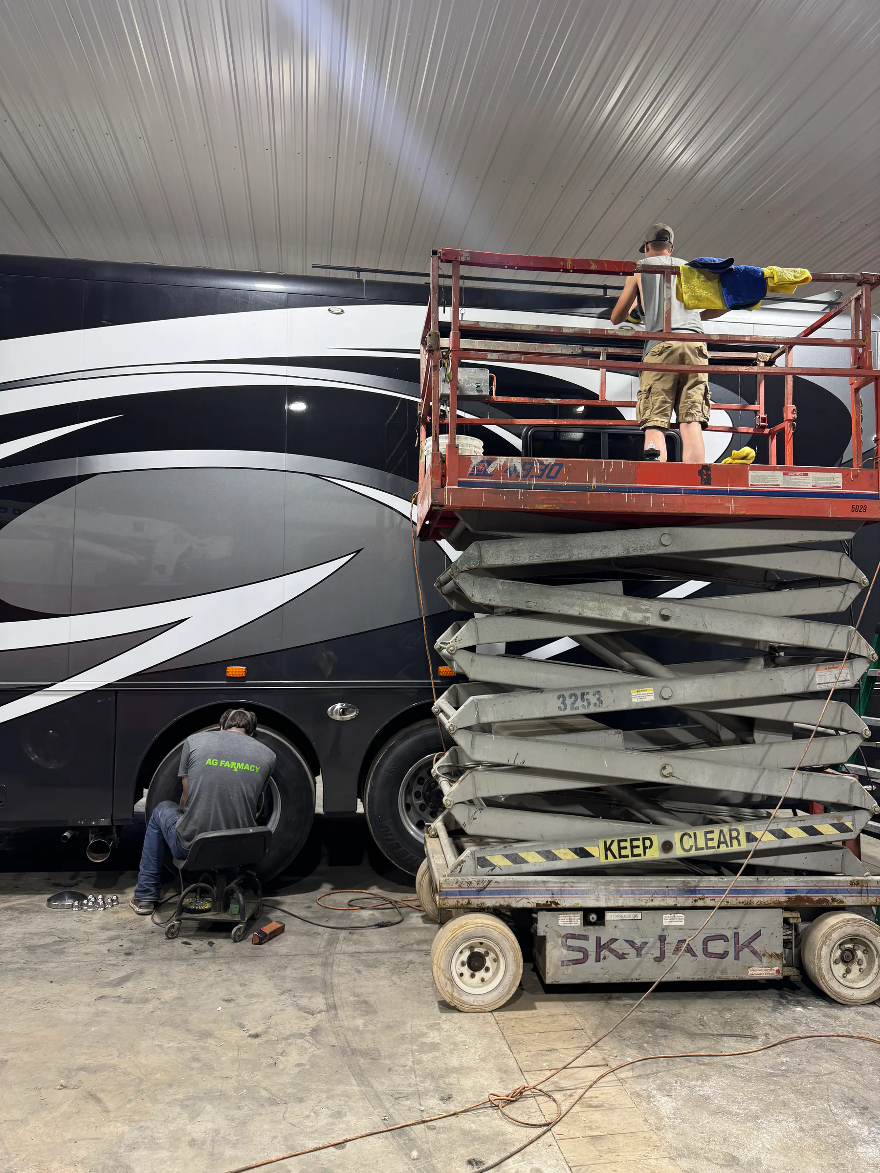 Technicians working from a lift beside a large motorhome