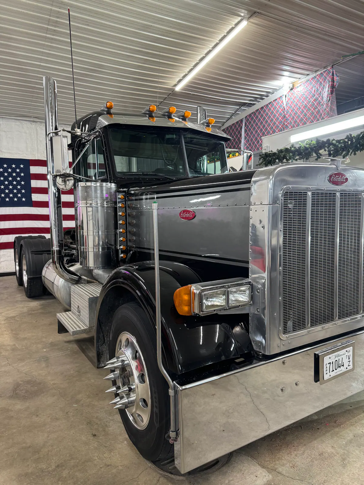 Polished black and chrome Peterbilt semi truck inside the shop