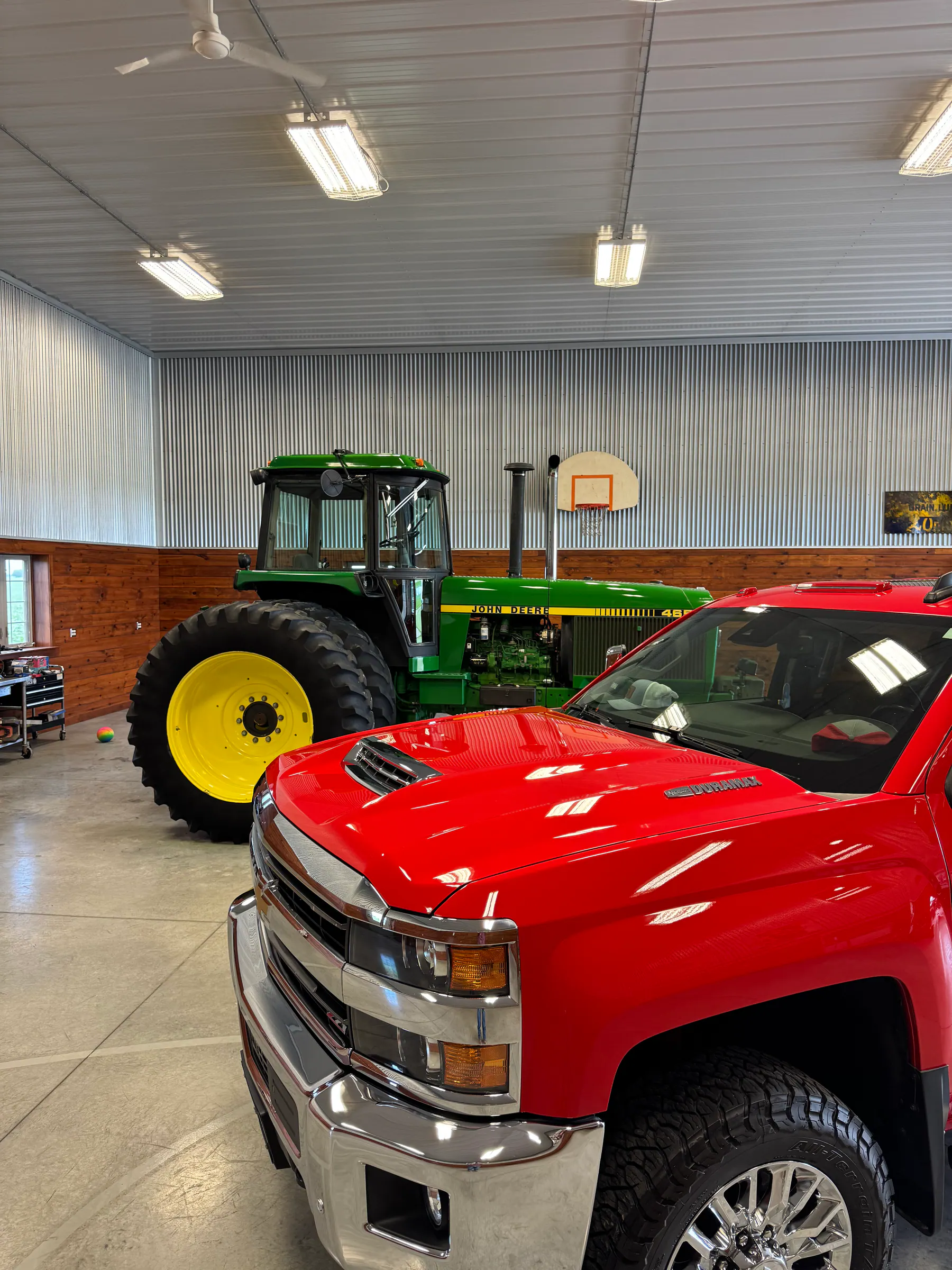 Red pickup and green tractor displayed together in a shop