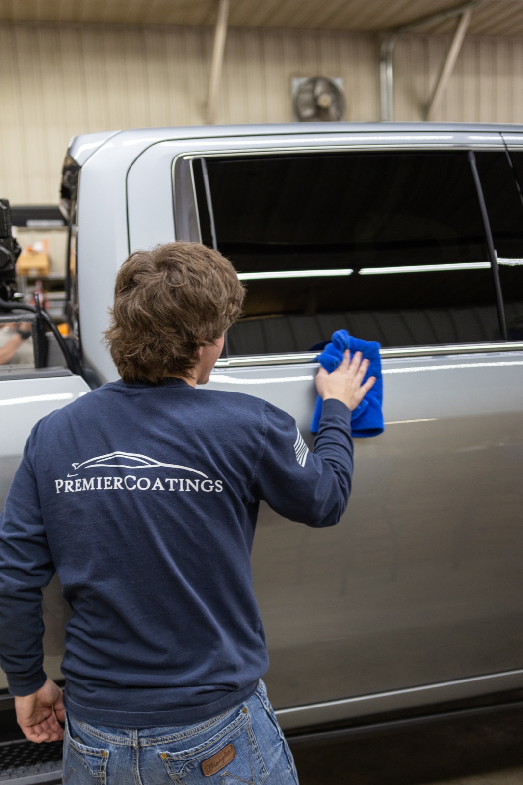 Premier Coatings team member finishing the exterior of a silver truck